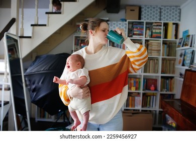 Tired mother with large cup of coffee and screaming baby in her arms. - Powered by Shutterstock