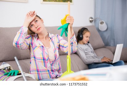 Tired Mother Sitting Near The Table With Mop After Cleaning Home