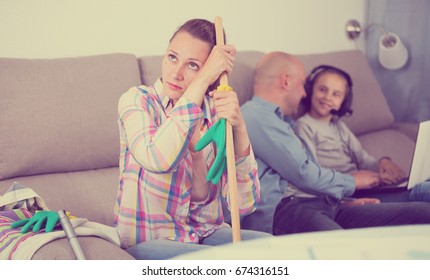 Tired Mother Sitting Near The Table With Mop After Cleaning Home