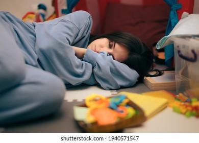 Tired Mother Sleeping On The Floor Surrounded By Toys. Exhausted Mom Resting In Messy Playroom
