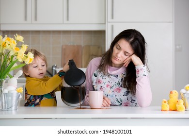 Tired Mother, Trying To Pour Coffee In The Morning. Woman Lying On Kitchen Table After Sleepless Night, Trying To Drink Coffee