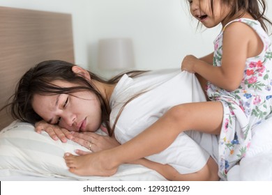 Tired Mother Trying To Sleep With Child Awake Playing. Morning Time. 