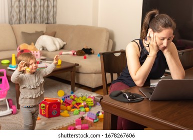 Tired Mother Trying To Work On A Laptop At Home During Her Kid Crying. Childcare And Working Mom Concept. Women Powerful. Toddler Tantrum. Young Lady Working At Home During Quarantine.