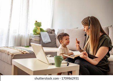 Tired Mother Trying To Work On A Laptop At Home During Her Kid Crying. Childcare And Working Mom Concept. Women Powerful. Toddler Tantrum. Young Lady Working At Home During Quarantine.