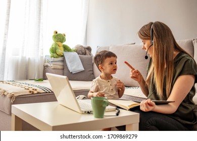 Tired Mother Trying To Work On A Laptop At Home During Her Kid Crying. Childcare And Working Mom Concept. Women Powerful. Toddler Tantrum. Young Lady Working At Home During Quarantine.