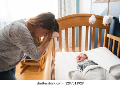 Tired Mother With Upset Baby Suffering With Post Natal Depression.