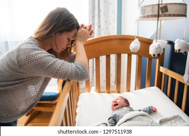 Tired Mother With Upset Baby Suffering With Post Natal Depression.