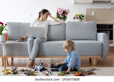 Tired Mother, Working On Her Laptop And Taking Phone Calls, Child Playing On The Floor At Home While Mom Having Home Office