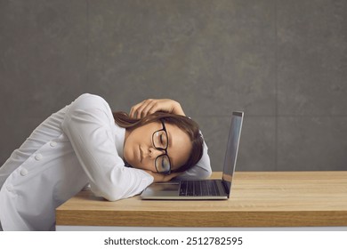 Tired office lady, secretary, bored intern, fatigued professional programmer sleeping lying down near laptop computer screen, face on keyboard, exhausted by tiresome workload or overtime work overload - Powered by Shutterstock