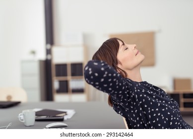 Tired Office Woman At Her Worktable, Leaning Her Back On A Chair With Hands At The Back Of Her Head And Eyes Closed, Emphasizing Of Thinking Something.