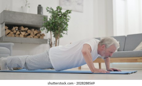Tired Old Man doing Pushups on Excercise Mat at Home