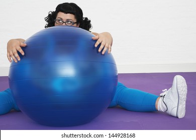 Tired Overweight Woman Sitting Behind Exercise Ball In Healthclub