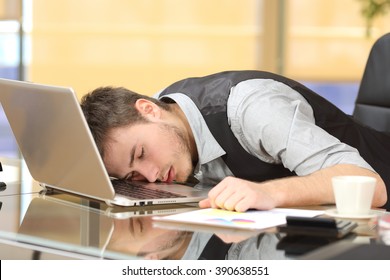 Tired overworked businessman sleeping over a laptop in a desk at job in his office