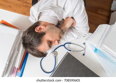 Tired Overworked Doctor Is Sleeping On Desk In Office. View From Above.