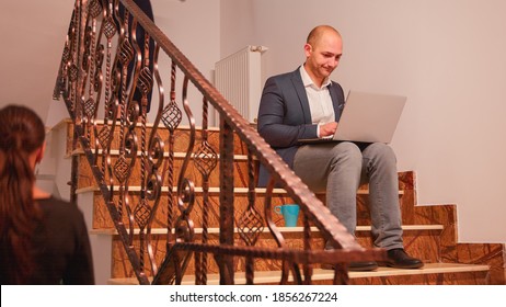 Tired Overworked Entrepreneur Smoking Working On Difficult Finance Deadline Sitting On Stairs. Business Man Doing Overtime At Corporate Job On Staircase While Colleagues Leaving Office Building.