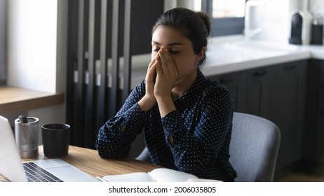 Tired overworked Indian employee feeling fatigue and burnout after working at laptop from home, suffering from head ache, eye sight vision problem, meditating for stress relief. Mental health concept