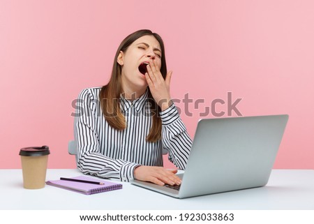 Tired overworked woman office worker yawning sitting at workplace with laptop, exhausted with job routine, showing disinterest. Indoor studio shot isolated on pink background Сток-фото © 