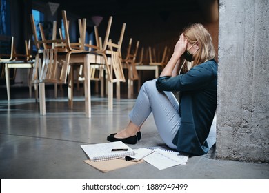 Tired owner sitting on floor in closed cafe, small business lockdown due to coronavirus. - Shutterstock ID 1889949499