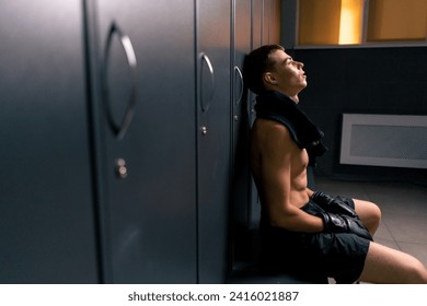 tired pensive boxer in boxing gloves sitting locker room after competition in ring - Powered by Shutterstock