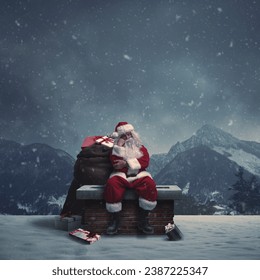 Tired pensive Santa Claus delivering Christmas gifts, he is sitting on a chimney under the snow and thinking - Powered by Shutterstock