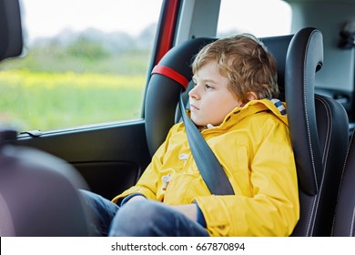 Tired Preschool Kid Boy Sitting In Car During Traffic Jam. Sad Little School Child In Safety Car Seat With Belt Looking Out Of Window.