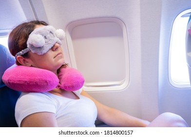 Tired Red-haired Woman Sleeping On The Plane With An Eye Mask And A Neck Pillow