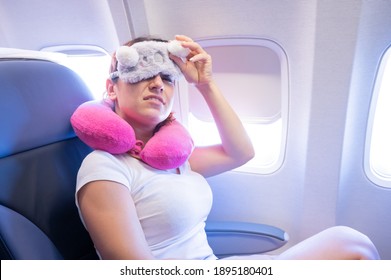 Tired Red-haired Woman Sleeping On The Plane With An Eye Mask And A Neck Pillow