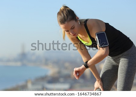 Tired runner checking smartwatch controlling pulsations after exercise