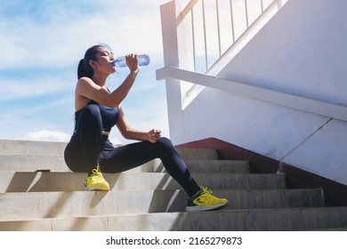 Tired runner woman with a bottle of electrolyte drink freshness after training outdoor workout at the stadium stairway. - Powered by Shutterstock