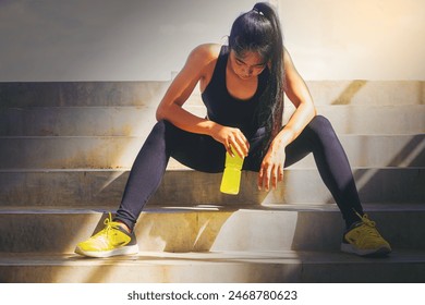 Tired runner woman with a bottle of electrolyte drink freshness after training outdoor workout at the stadium stairway. - Powered by Shutterstock