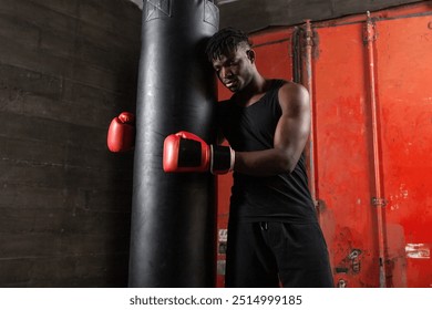 tired sad african american boxer in red gloves stands with his hands down near punching bag and thinks, unhappy puzzled athlete loses and is depressed - Powered by Shutterstock