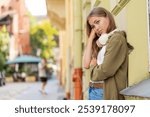 Tired sad Caucasian woman feeling worried about financial problem stress outdoor. Upset female girl frustrated thinking of money debt budget loss bankruptcy leaning on wall on urban street. Horizontal