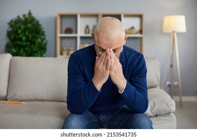 Tired, sad, depressed senior man sitting on sofa, holding face in hands, looking down, feeling devastated by problems, regretting mistakes of past, or, scared of loneliness, grieving over loss of wife - Powered by Shutterstock