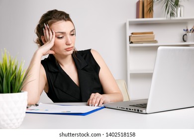Tired sad woman in stress sitting at her workplace and working on the computer.