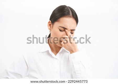 Tired saleswoman, young asian woman in office, massages her eyes, has fatigue after work, isolated on white background.
