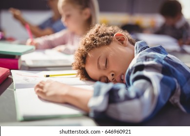 Tired schoolboy sleeping in classroom at school - Powered by Shutterstock