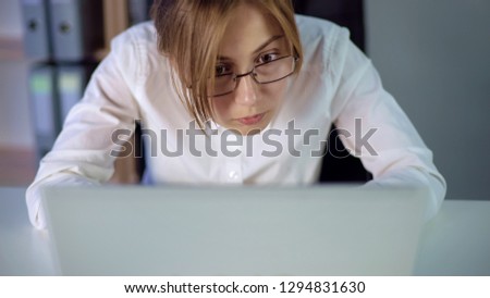 Tired secretary in eyeglasses attentively looking at computer screen, eye strain