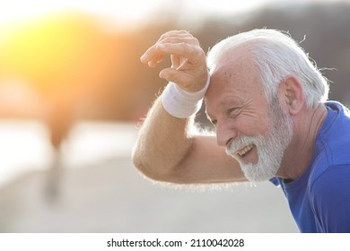 Tired senior bearded man wiping sweat from his forehead with wristband after outdoor exercise - Powered by Shutterstock