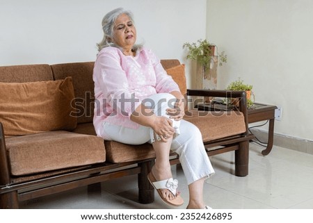 Tired, Senior gray haired woman holding her knee suffering from Joint pain