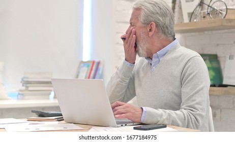 Tired Senior Old Man Yawning While Using Laptop