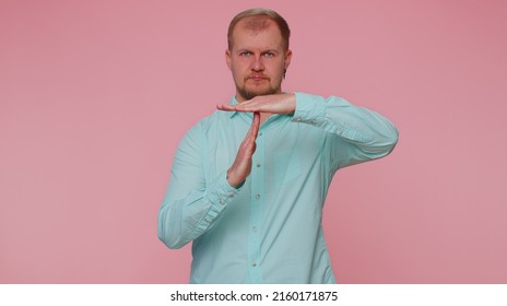 Tired Serious Upset Man 30s In Blue Shirt Showing Time Out Gesture, Limit, Stop Break Sign, No Pressure, I Need More Time. Young Adult Blonde Guy Boy Isolated Alone On Pink Studio Wall Background