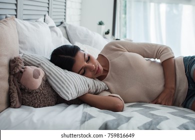 So tired. Side view of beautiful young woman sleeping while lying down on her bed