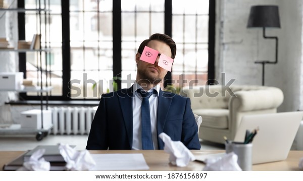 Tired sleepy businessman with stickers, adhesive\
notes on eyes sleeping at workplace, sitting at work desk in\
office, unproductive lazy employee executive dozing, working on\
difficult project