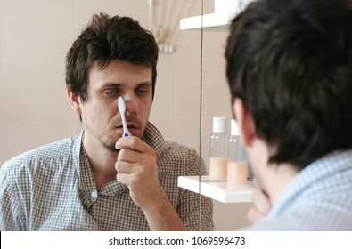 Tired Sleepy Man With A Hangover Who Has Just Woken Up To Brush His Teeth, Looks At His Reflection In The Mirror.