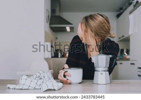 Tired sleepy person female having some problems. Exhausted woman with coffee at home. Сoncept of woman or mother in depression, burnt out, tired from work or study, unsatisfactory with her life.