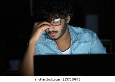 Tired Sleepy Stressed Overworked Young Indian Business Man Student Wearing Glasses Feeling Lack Of Sleep, Having Eyestrain Vision Problem, Using Laptop Computer Working Late At Night At Home Office.