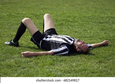 The Tired Soccer Player Is Lying Down On The Grass On Playing Field, Finished Football Match.