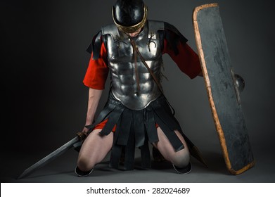 Tired Soldier Kneeling With A Shield And A Sword In Hands