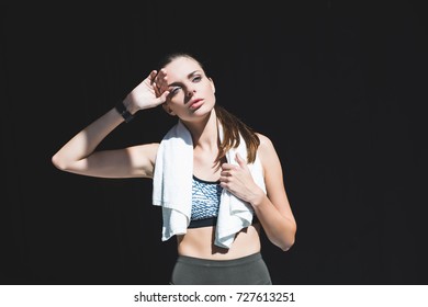 Tired Sportswoman With Towel Wiping Sweat After Workout And Looking Away Isolated On Black