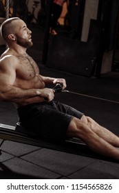 A Tired Sporty Man Sitting On The Indoor Rower At Gym. People And Fitness Concept